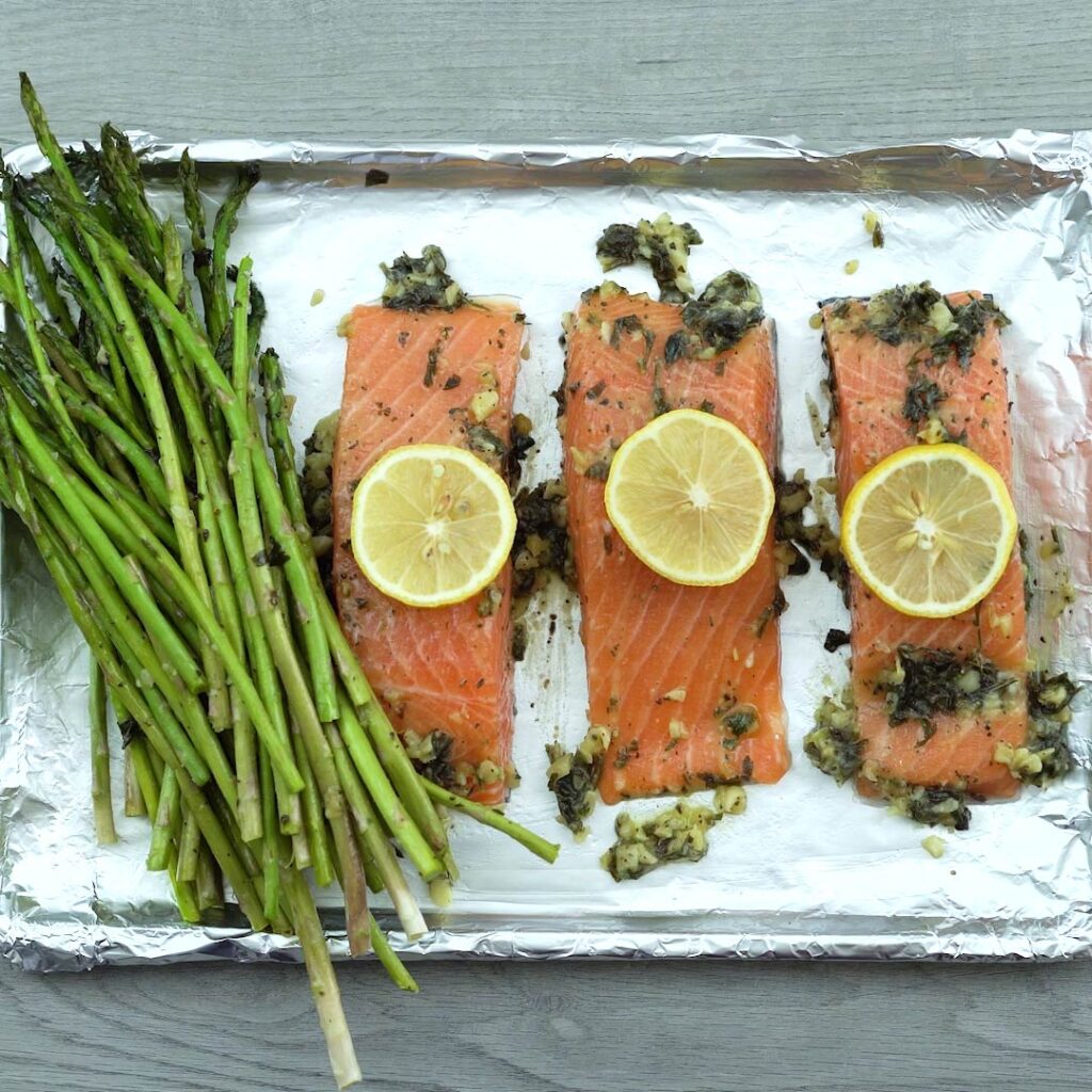 asparagus and salmon fillets in foiled baking sheet