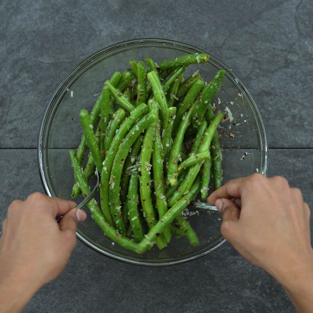 tossing the green beans with the seasoning