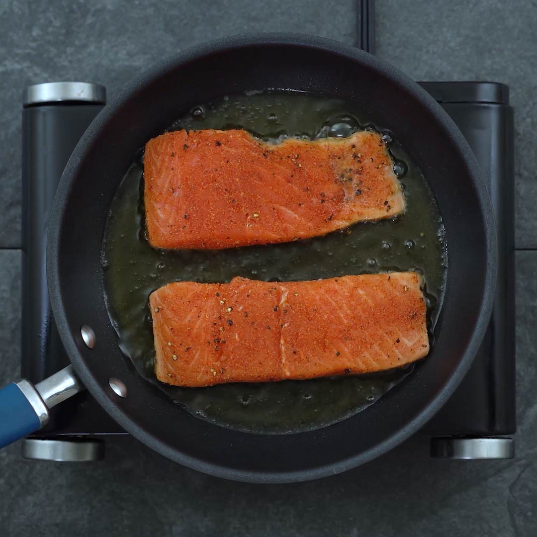 Salmon fillets with seasoning on a plate pan frying the seasoned salmon fillets